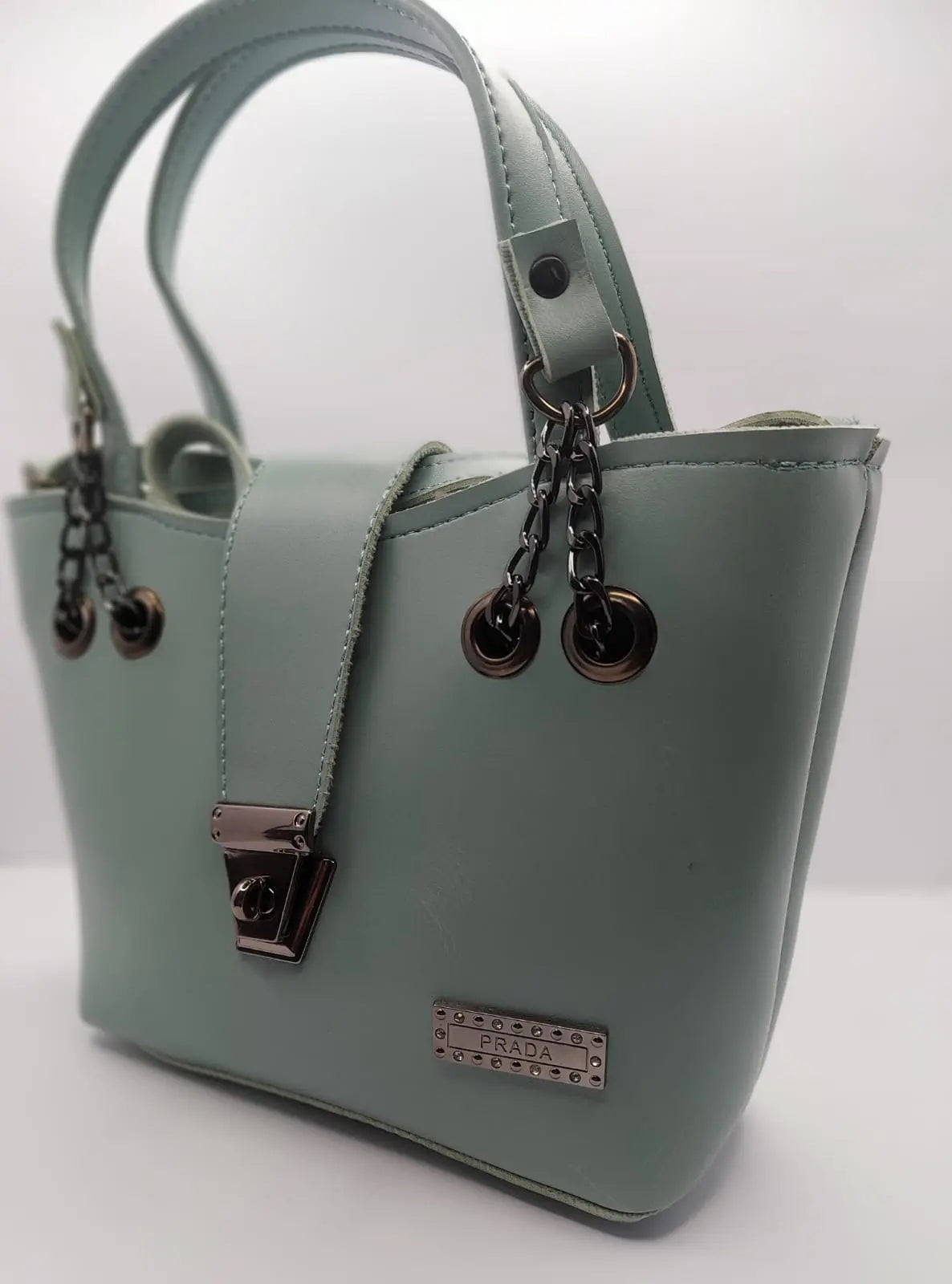 Mint Green tote bag with metallic twisted lock, crafted from premium PU leather. Features hand tote and adjustable shoulder straps, dual zippers fot storage, and a sleek solid design with metallic details. Ideal for daily use or special occasions